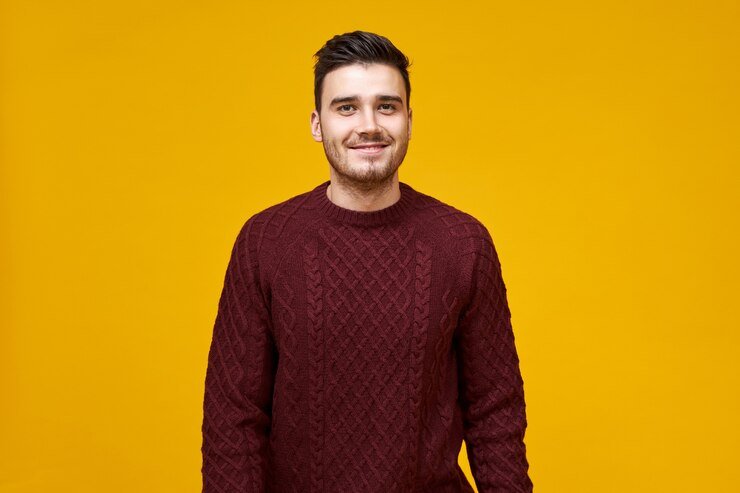 handsome-cheerful-young-man-with-stylish-haircut-dimpled-smile-posing-isolated-against-blank-yellow-wall-dressed-cozy-maroon-sweater-having-confident-look_343059-4609